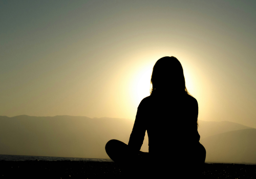 séjour en montagne une femme qui médite devant le coucher du soleil